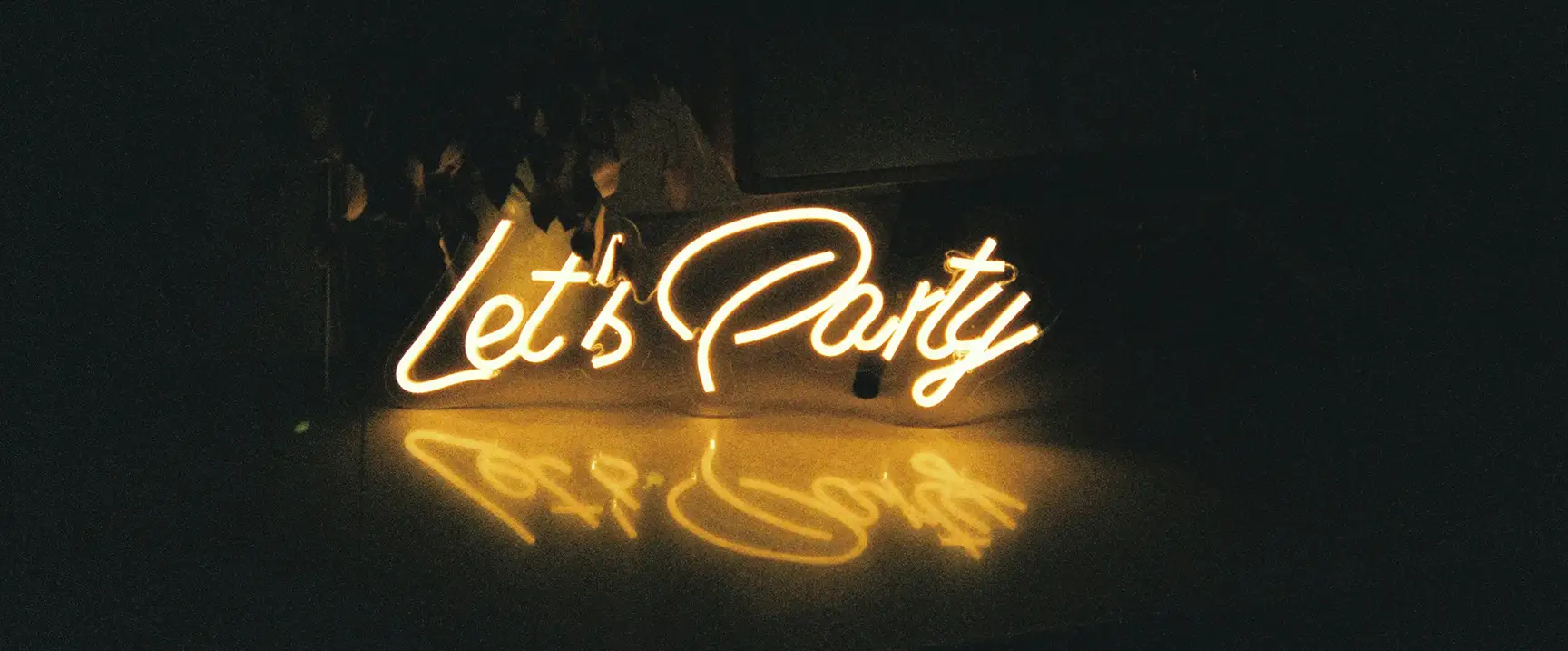 Leuchtendes 'Let's Party' Neon-Schild im Ambiente der LuSt Café/Bar